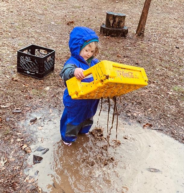 Toddler in rain suit playing in water