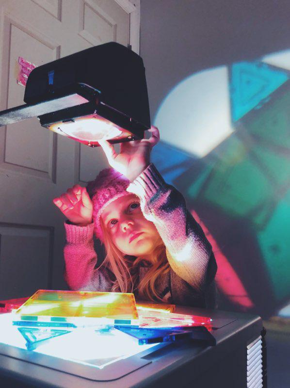 Little girl playing with colorful slides on a projector