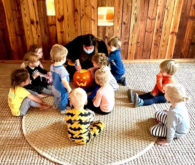 Children gathering with teacher to carve a pumpkin
