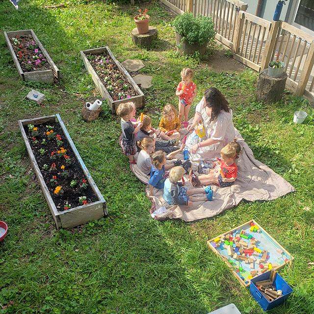 Children gathered in outdoor play area with teacher